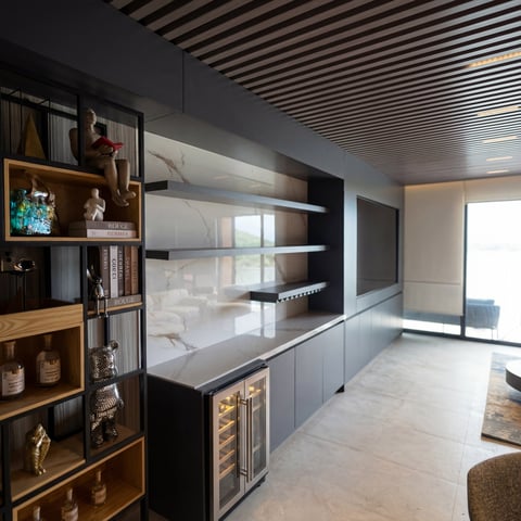 Modern kitchen with black and wood cabinetry, built-in shelving, and sleek design with tile flooring and striped ceiling
